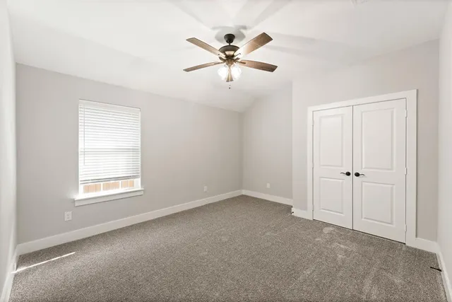 a view of an empty room with a ceiling fan and a window