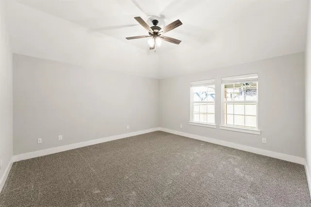 an empty room with chandelier fan and windows