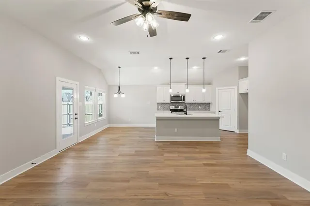 a large kitchen with kitchen island a sink stainless steel appliances and a chandelier