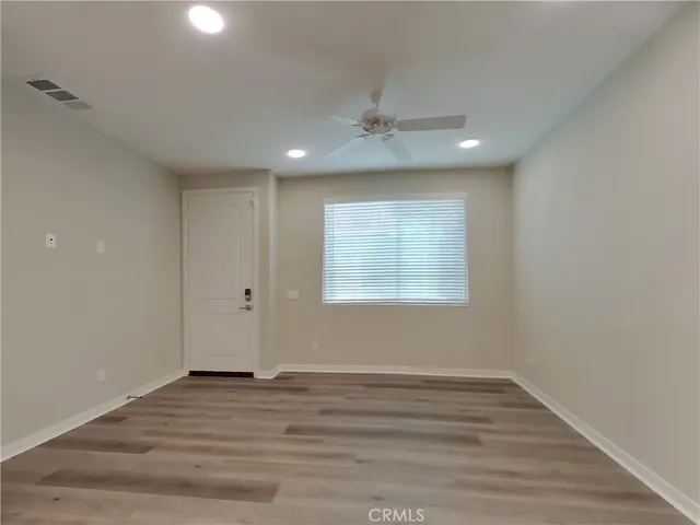 an empty room with wooden floor cabinet and windows