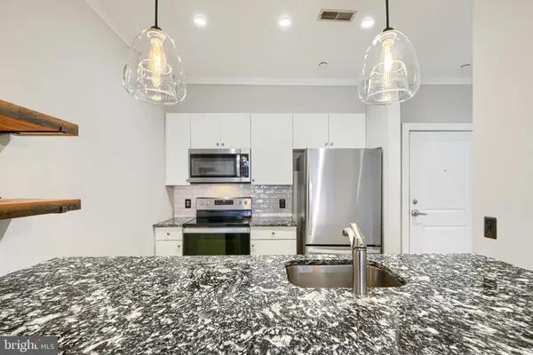 a kitchen with kitchen island granite countertop stainless steel appliances a stove refrigerator and microwave