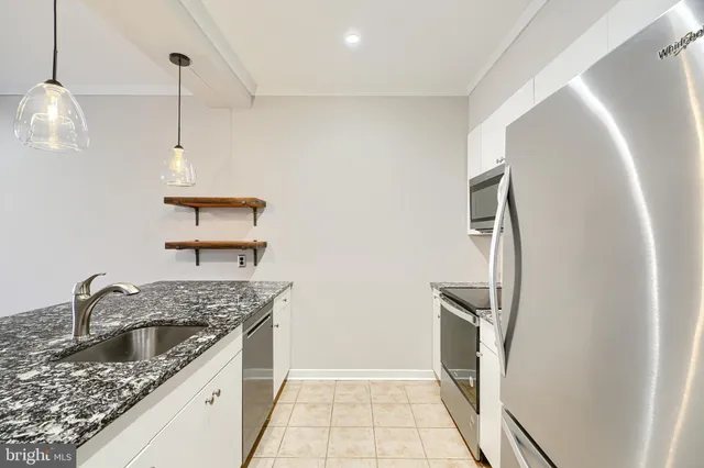 a kitchen with a sink a granite counter top space and cabinets