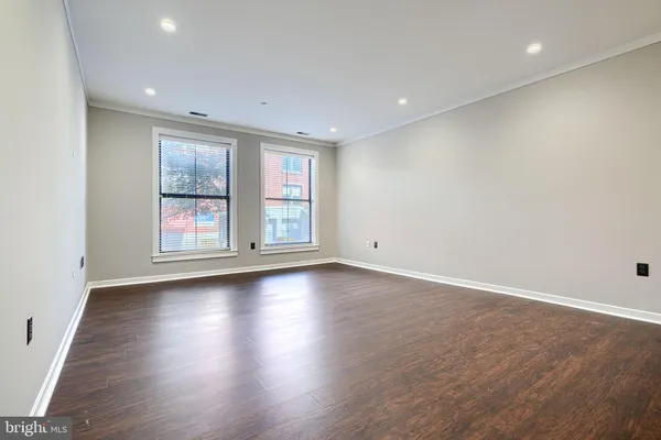 an empty room with wooden floor and windows