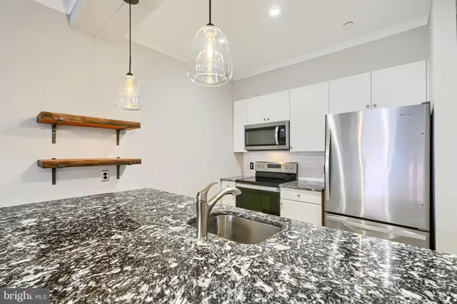 a kitchen with stainless steel appliances granite countertop a sink refrigerator stove and microwave