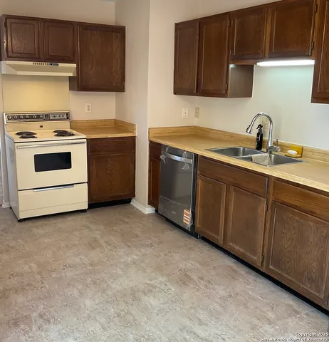 a kitchen with sink a stove and cabinets