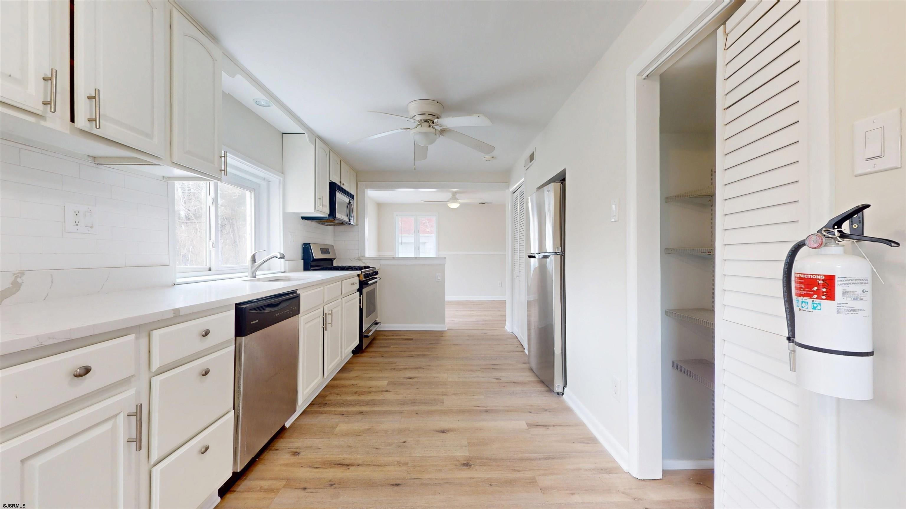4 East Mill Road Northfield, NJ 08225 - Photo 8 of 49 a kitchen with white cabinets and white appliances