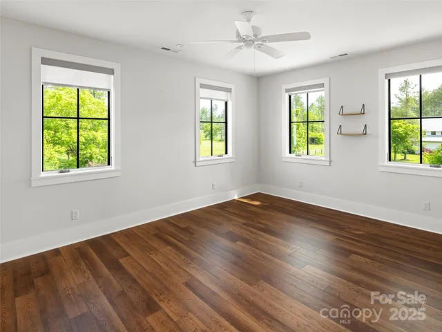 a view of empty room with wooden floor and fan
