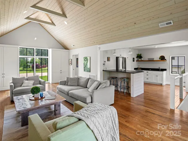 a view of a white house with a big yard plants and large trees