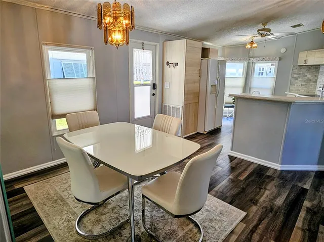 a metallic refrigerator sitting in a kitchen next to a window