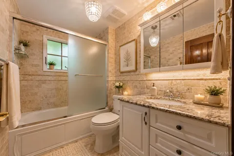 a bathroom with a granite countertop sink a toilet a mirror and shower