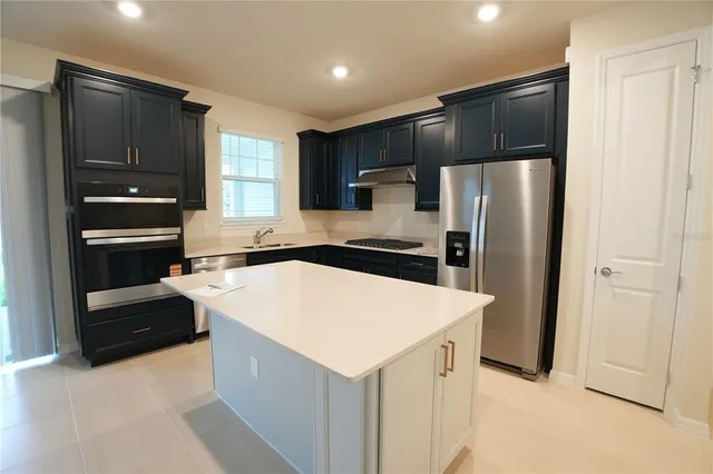 a kitchen with kitchen island a refrigerator and a stove