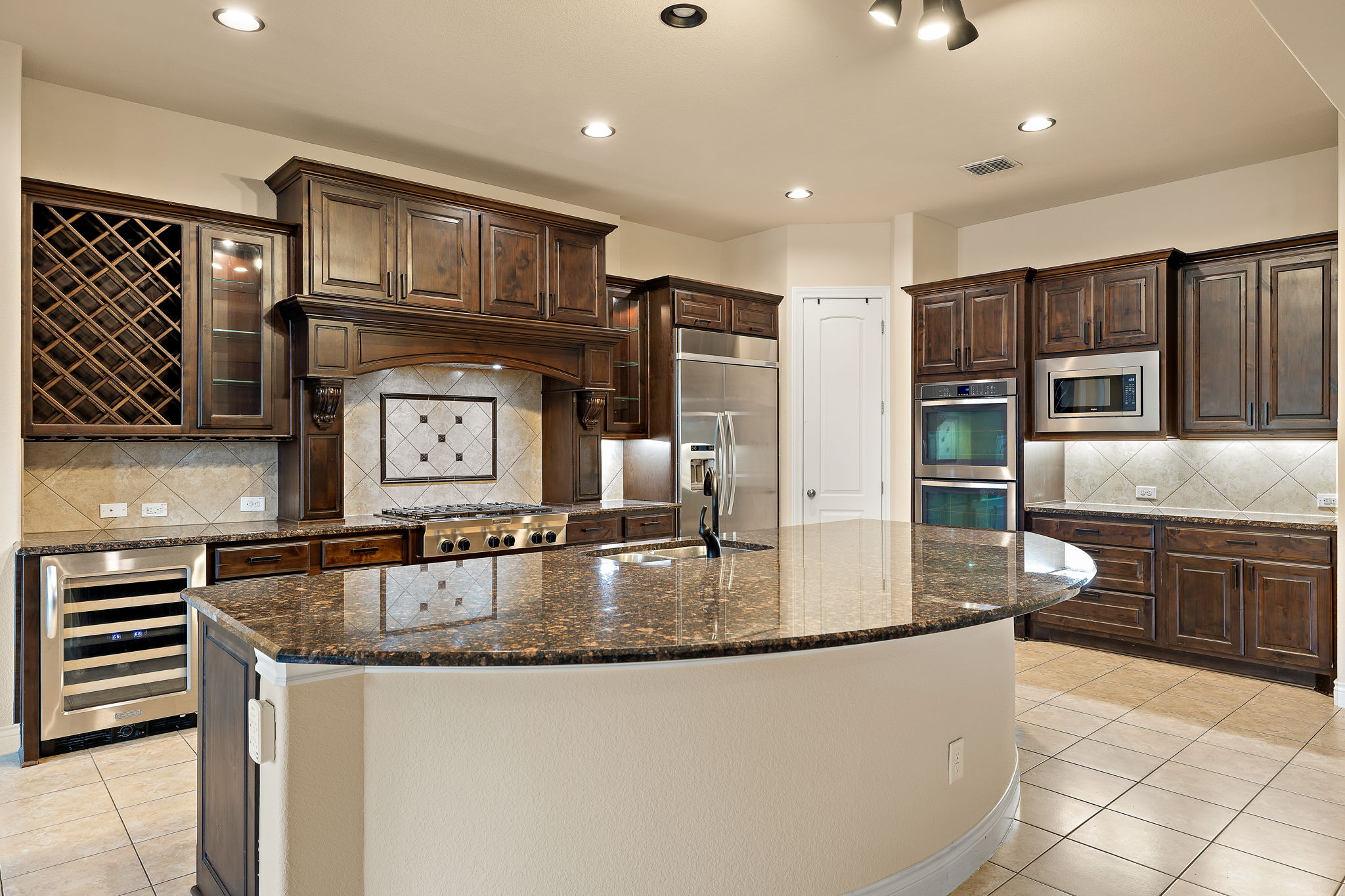 174 Estrella Crossing Georgetown, TX 78628 - Photo 11 of 38 Kitchen with backsplash, light tile patterned floors, dark brown cabinetry, wine cooler, and recessed lighting