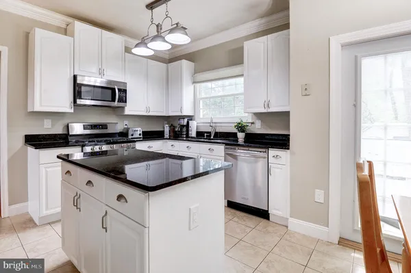 a kitchen with white cabinets granite counter tops and a stove