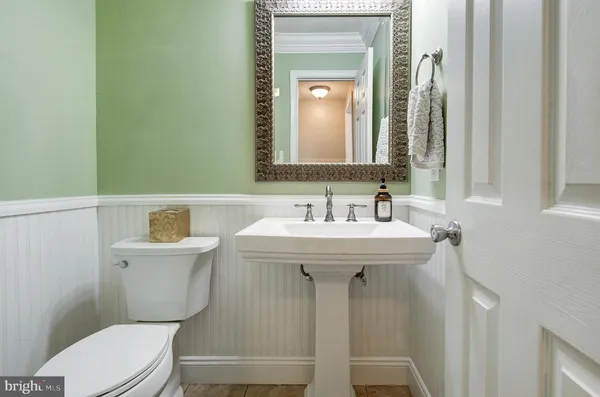 a bathroom with a sink a mirror a toilet and a window