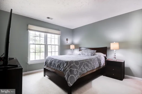 a bedroom with a bed and a flat tv screen on a dresser
