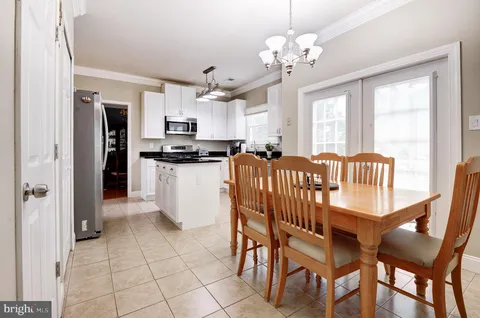 a kitchen with stainless steel appliances granite countertop a dining table chairs and refrigerator