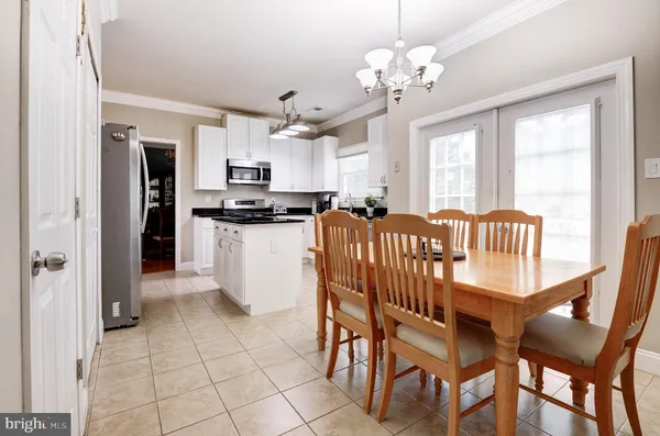 a kitchen with stainless steel appliances granite countertop a dining table chairs and refrigerator