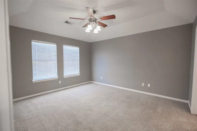 an empty room with windows and chandelier fan