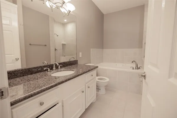 a bathroom with a granite countertop sink mirror vanity and toilet