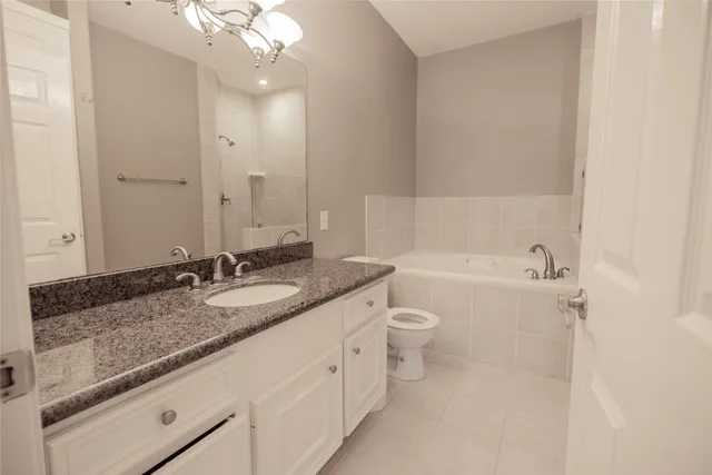 a bathroom with a granite countertop sink mirror vanity and toilet