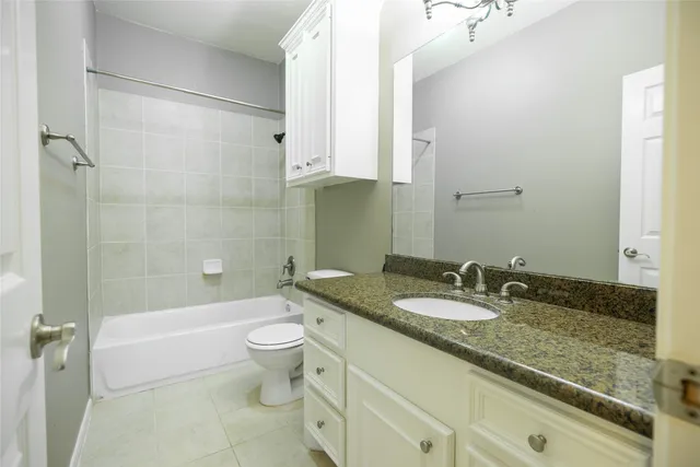a bathroom with a granite countertop sink a toilet a mirror and shower