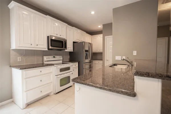 a kitchen with stainless steel appliances granite countertop a sink a microwave and refrigerator