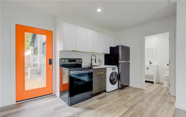 a view of kitchen with stainless steel appliances granite countertop a stove a refrigerator and a view of living room