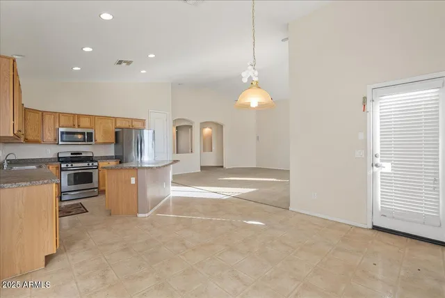 a kitchen with stainless steel appliances granite countertop a refrigerator a sink a stove and white cabinets