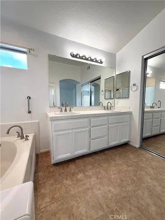 a bathroom with a double vanity sink a mirror and bathtub
