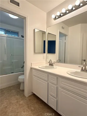 a bathroom with a double vanity sink toilet mirror and bathtub