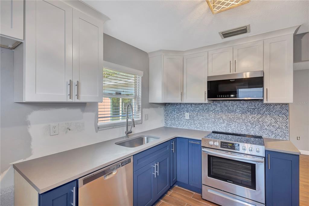 7737 Mitchell Ranch Road New Port Richey, FL 34655 - Photo 9 of 27 a kitchen with stainless steel appliances a stove a microwave sink and cabinets