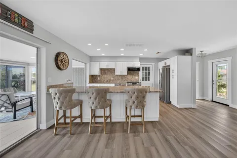 a view of kitchen with stainless steel appliances kitchen island granite countertop a table chairs and a stove