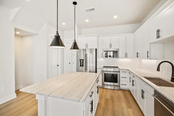 a kitchen with stainless steel appliances kitchen island a stove a sink a refrigerator a center island a stove and a wooden floors