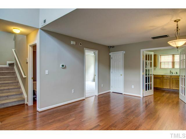 4512 Nightfall Court Durham, NC 27713 - Photo 7 of 24 a view of an empty room with wooden floor and a kitchen