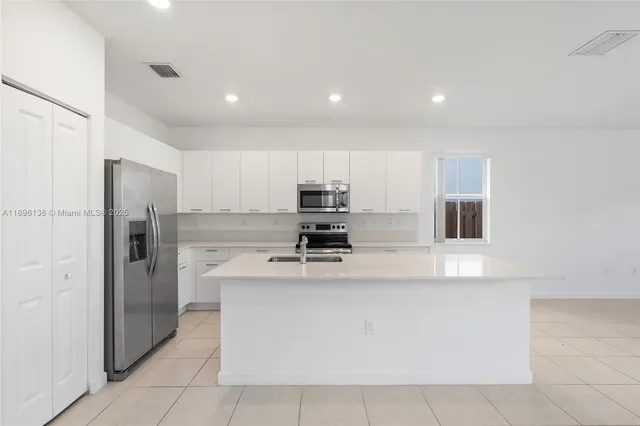 a view of kitchen with stainless steel appliances granite countertop a stove and a refrigerator