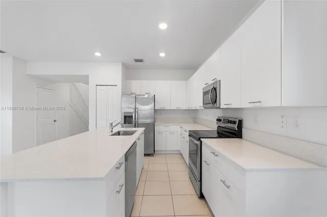 a kitchen with a sink a stove top oven and white stainless steel appliances