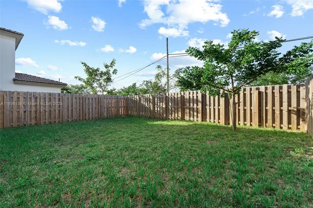 a view of backyard with potted plants and wooden fence