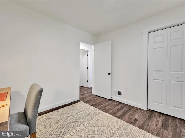 a view of a bedroom with wooden floor and a chair