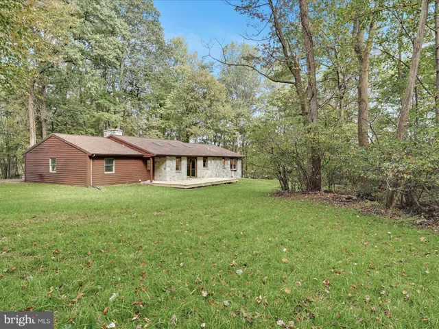 a view of a house with a big yard and large trees