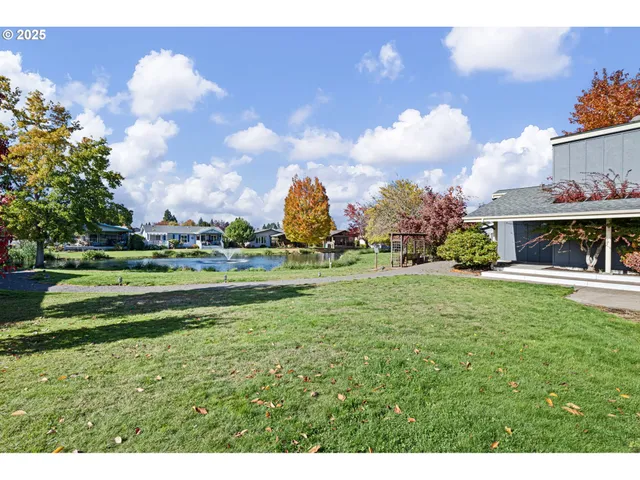 a view of house with a big yard and large trees