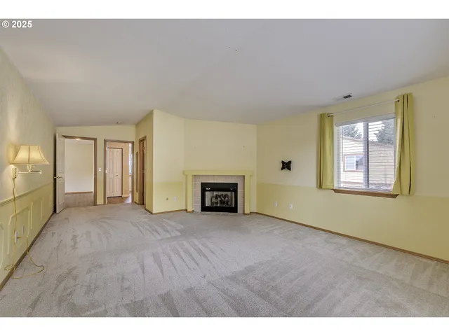 a view of an empty room with a window and fireplace