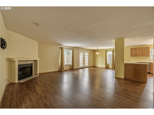 a view of an empty room with wooden floor and a fireplace