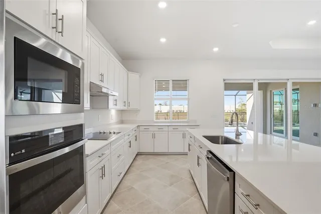 a open kitchen with stainless steel appliances granite countertop a sink and dishwasher a stove top oven with wooden floor