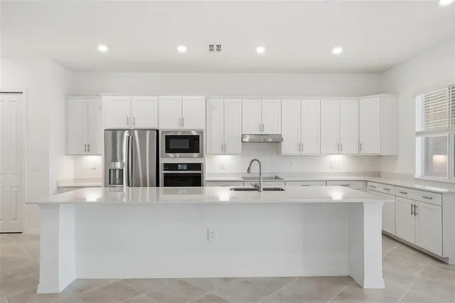 a kitchen with kitchen island granite countertop stainless steel appliances a sink a stove a microwave and cabinets