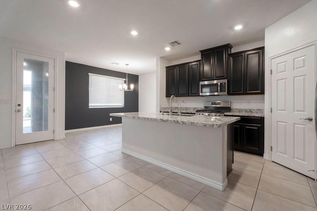 7126 Calvert Cliffs Street North Las Vegas, NV 89084 - Photo 7 of 44 A well-appointed kitchen features a central island, black cabinetry, and stainless-steel appliances.