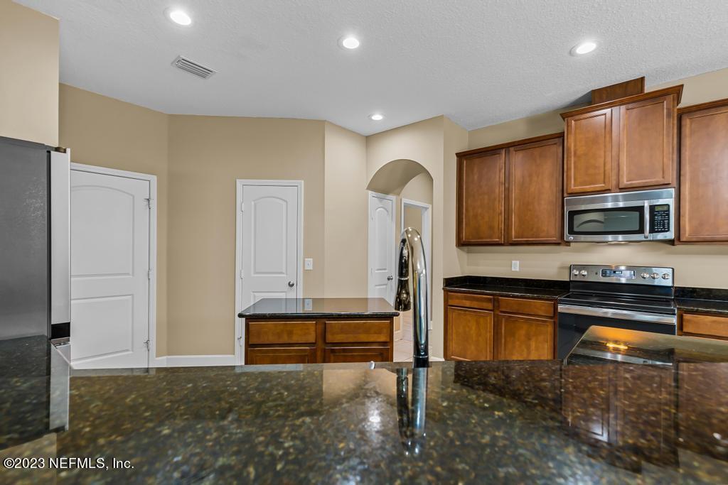 126 Arabian Court St. Augustine, FL 32095 - Photo 40 of 62 a kitchen with stainless steel appliances granite countertop a refrigerator and a stove top oven