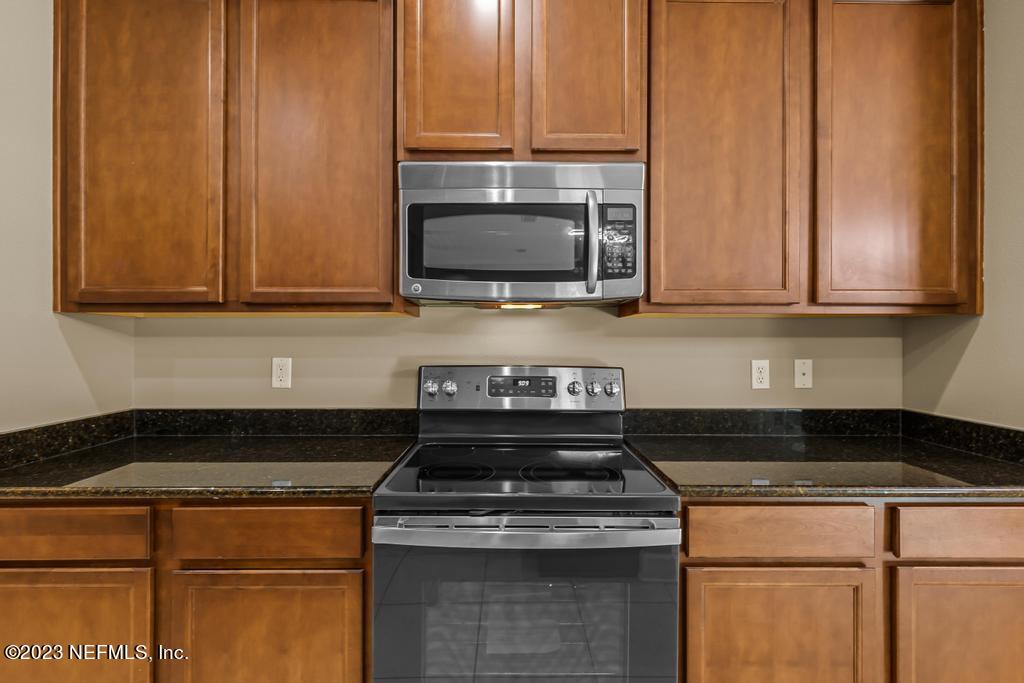 126 Arabian Court St. Augustine, FL 32095 - Photo 42 of 62 a kitchen with granite countertop wood cabinets and stainless steel appliances