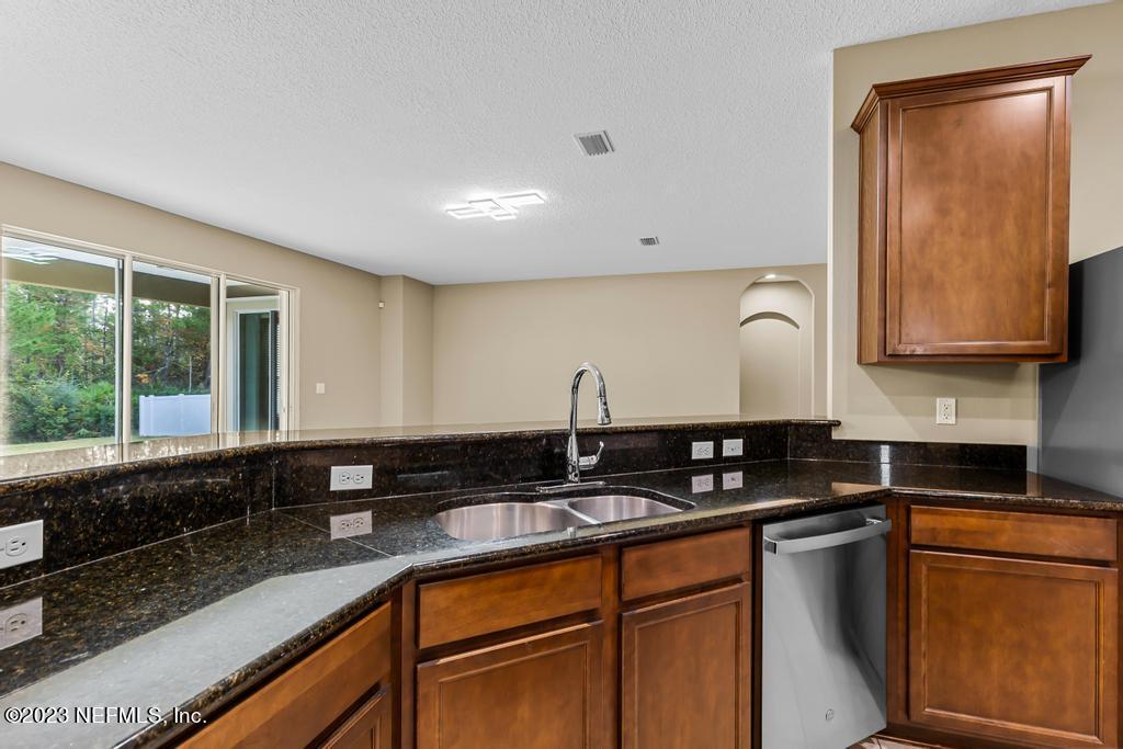 126 Arabian Court St. Augustine, FL 32095 - Photo 43 of 62 a kitchen with granite countertop a sink a stove and cabinets