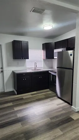 a kitchen with kitchen island a refrigerator and a sink