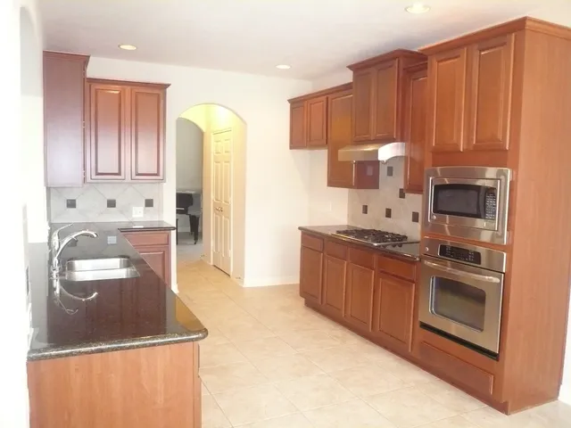 a kitchen with stainless steel appliances granite countertop a stove a sink and a refrigerator with wooden cabinets